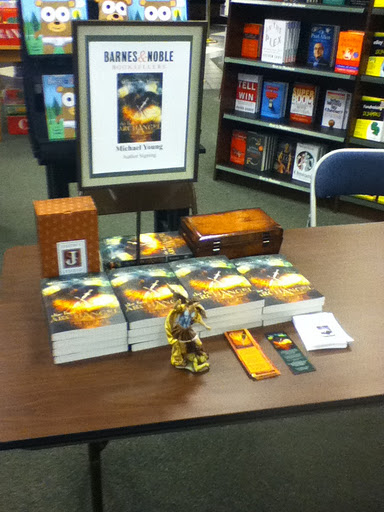 The Last Archangel signing table with books, bookmarks, an angel statue, and a music box